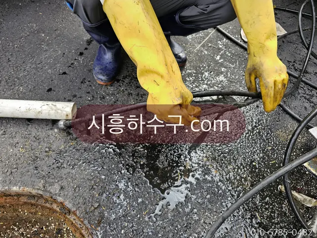 옥외 하수구에 스프링 장비를 넣어 뚫는 모습