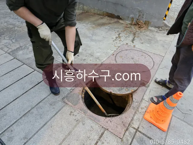 보도 위 맨홀을 열고 상태를 확인하는 작업