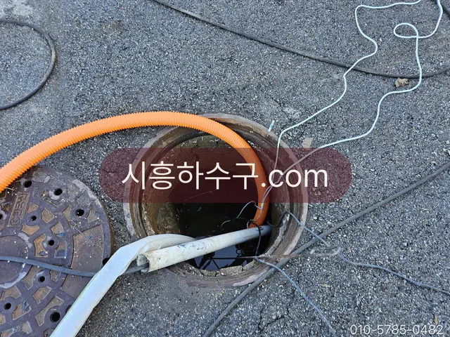 마당 맨홀 뚜껑을 열고 매설 하수관에 고압세척 호스를 넣는 작업